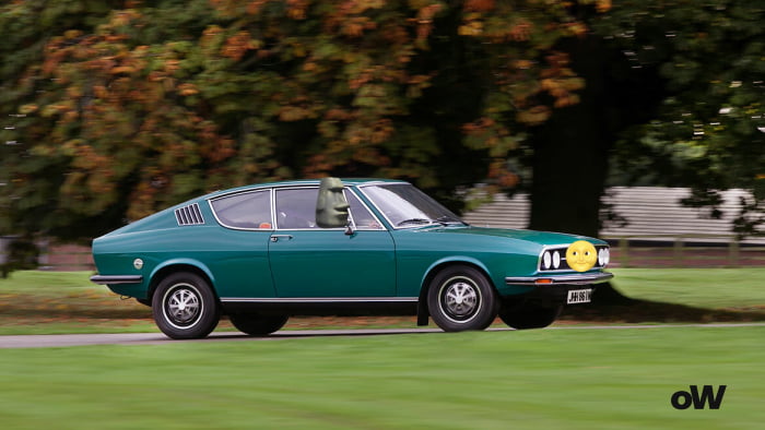 A rare green car is driving on the road