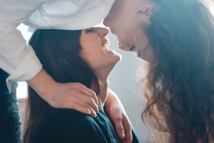 Close up young woman thoughtfully kissing woman at home