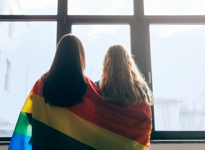 Lesbian sweethearts wrapped in lgbt flag